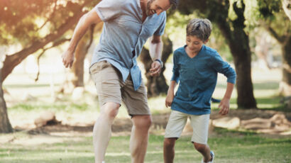 Padre e hijo jugando con una pelota de fútbol.