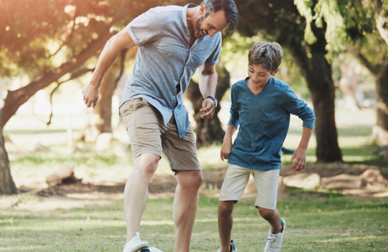 Padre e hijo jugando con una pelota de fútbol.