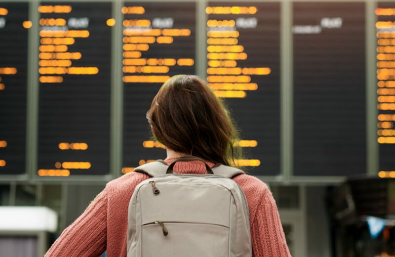 Mujer mirando una pantalla de información de vuelos del aeropuerto.