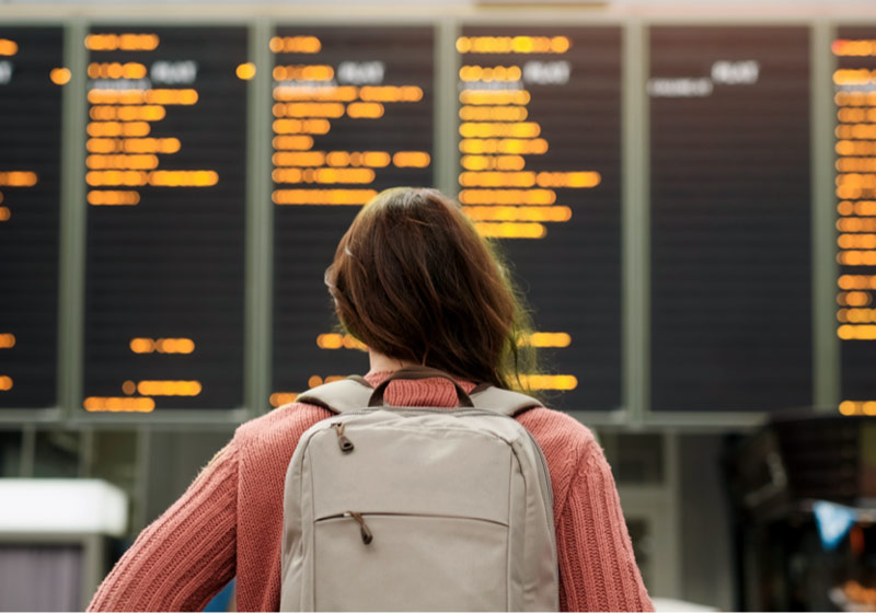 Mujer mirando una pantalla de información de vuelos del aeropuerto.