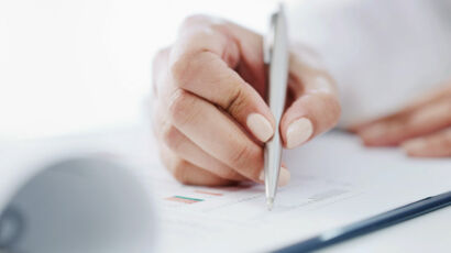 Primer plano de la mano de una mujer firmando un documento.