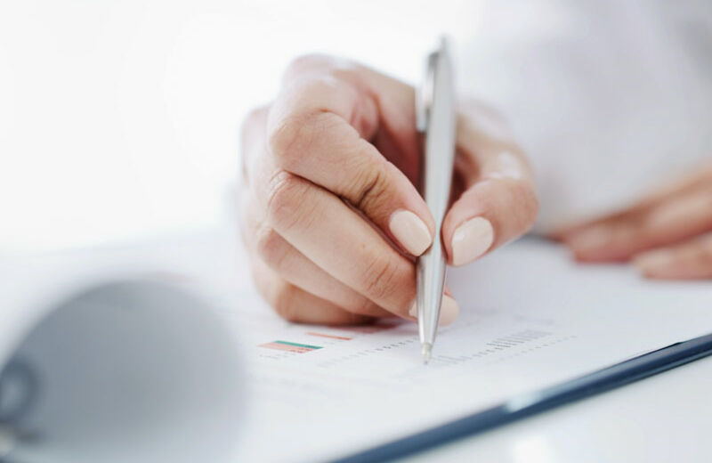 Primer plano de la mano de una mujer firmando un documento.