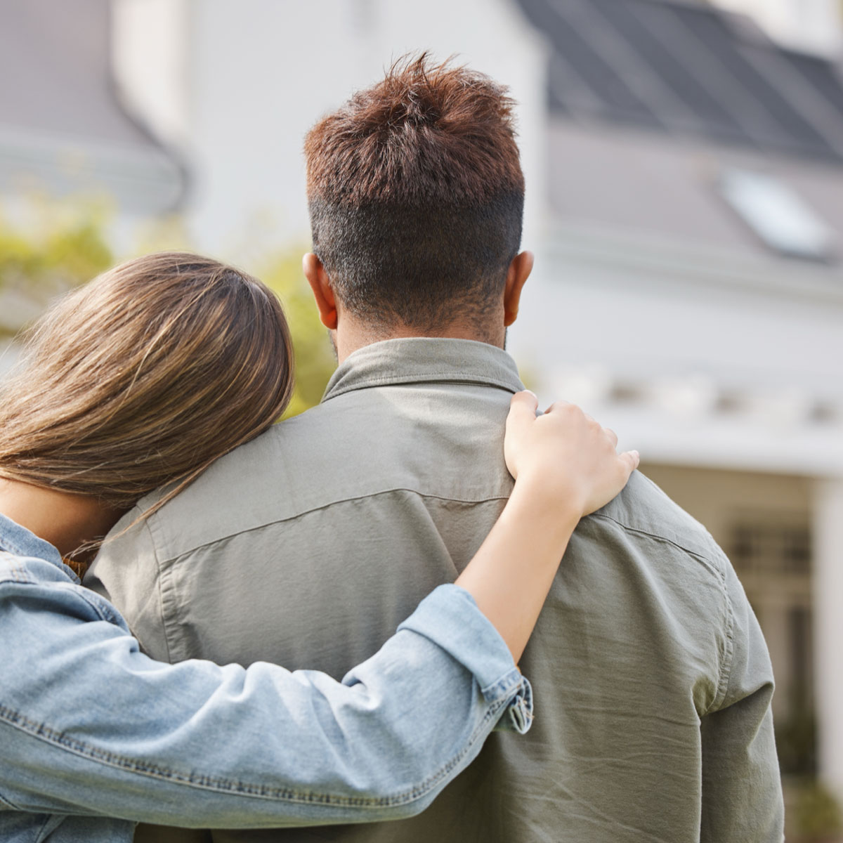 Pareja abrazados mirando una casa
