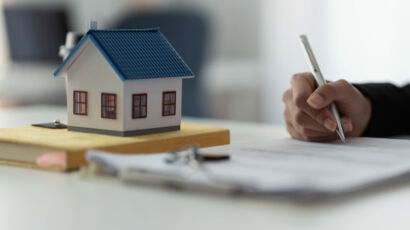Maqueta de una casa y una persona firmando unos documentos.